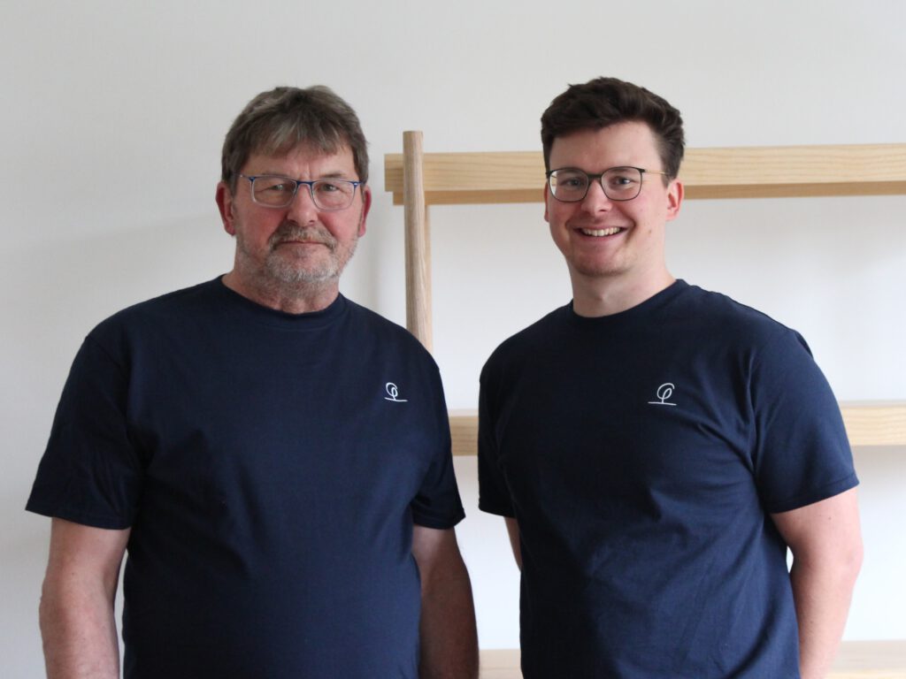Tischlermeister Felix Zintel und sein Mitarbeiter vor seinem Meisterstück, einem Regal in Esche.